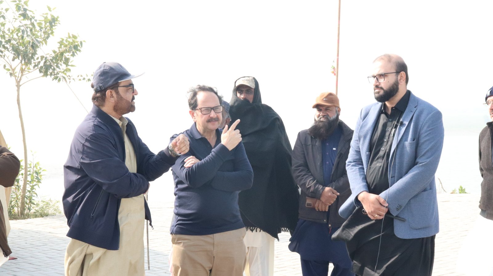 Bilal Anwar and colleagues in conversation on the bank of a canal