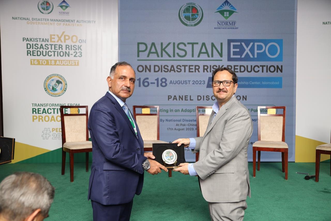 Bilal Anwar receiving a shield at the Pakistan Expo on Disaster Risk Reduction, in front of the NDMA and NDRMF panel backdrop
