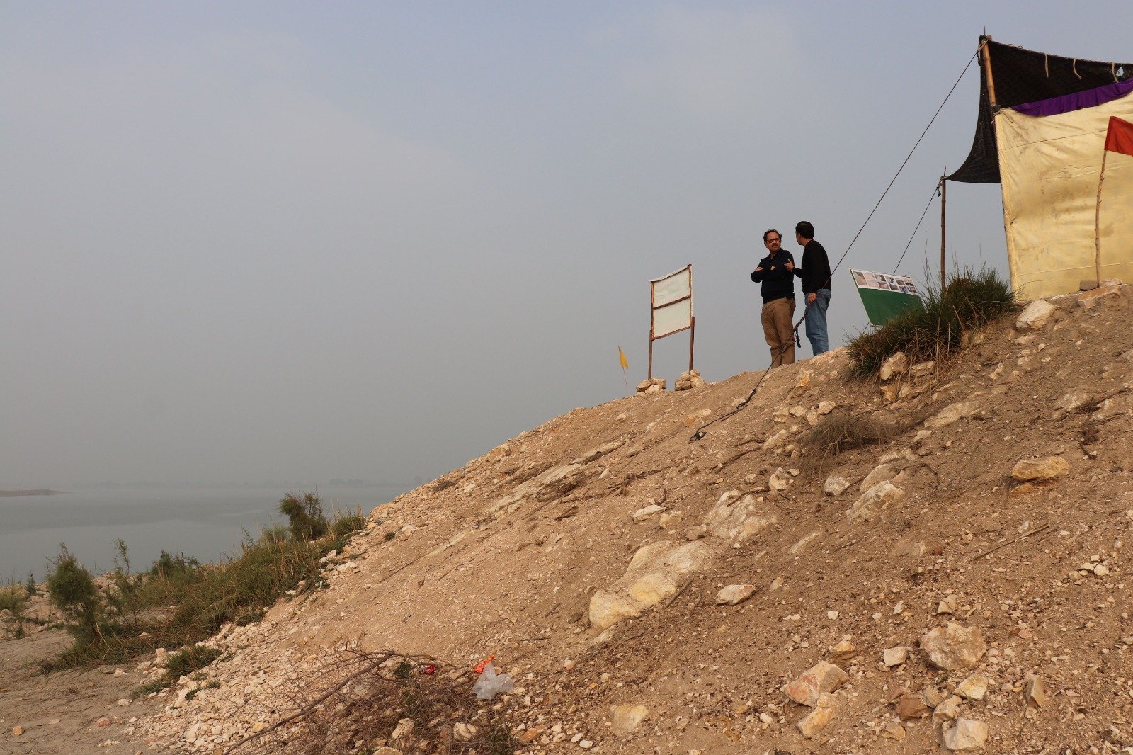 Two figures on an embankment ridge overlooking the river at Sujawal, Sindh
