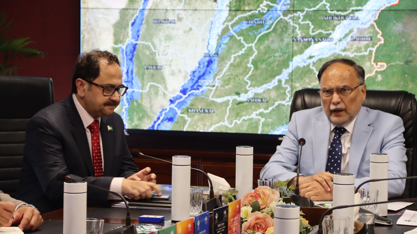 Bilal Anwar briefing beside a national flood inundation map