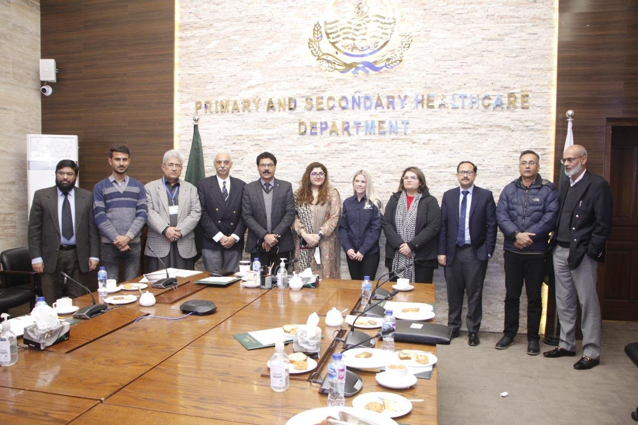 Bilal Anwar with colleagues around a conference table, the Primary and Secondary Healthcare Department backdrop behind them