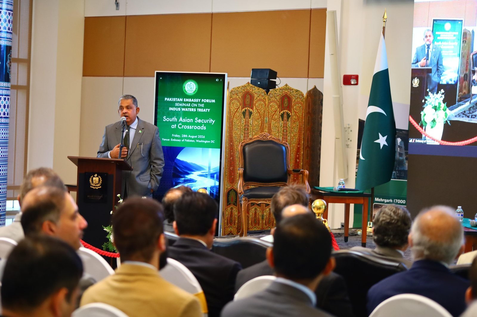 Bilal Anwar speaking from the lectern at the Pakistan Embassy Forum seminar on the Indus Waters Treaty, the banner for South Asian Security at Crossroads beside him