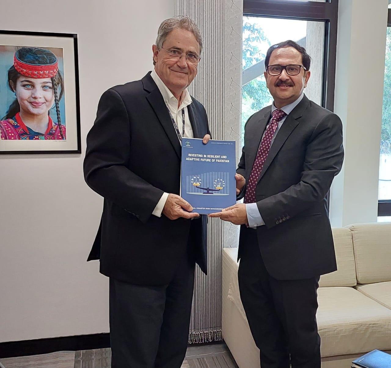 Bilal Anwar handing over the report Investing in a Resilient and Adaptive Future of Pakistan in a different office