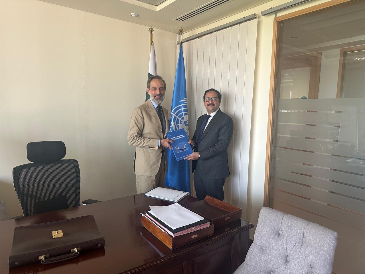 Bilal Anwar presenting the same report in a United Nations office, the UN and Pakistan flags behind