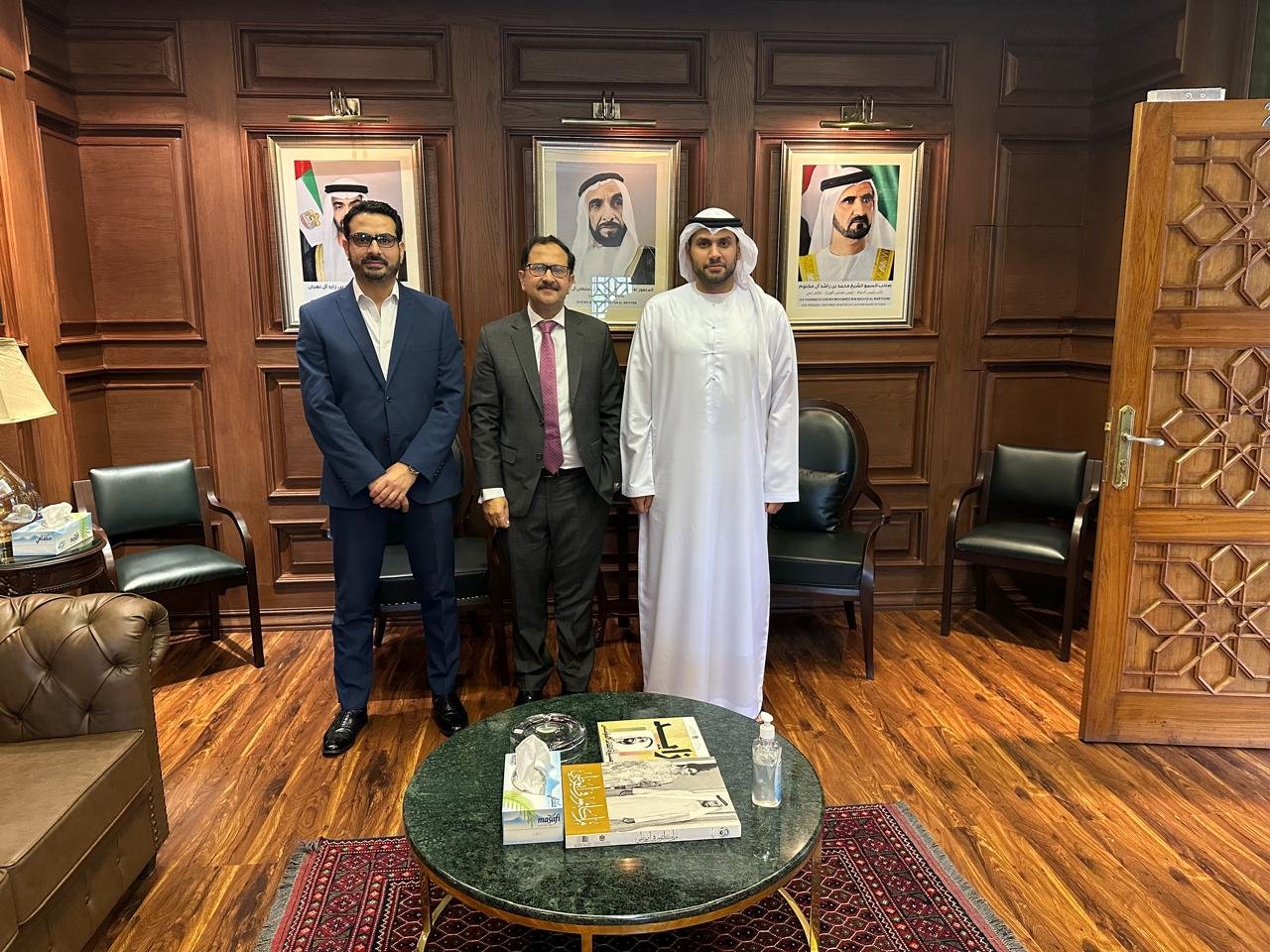 Bilal Anwar with his hosts after the meeting, portraits of the UAE leadership on the wall behind