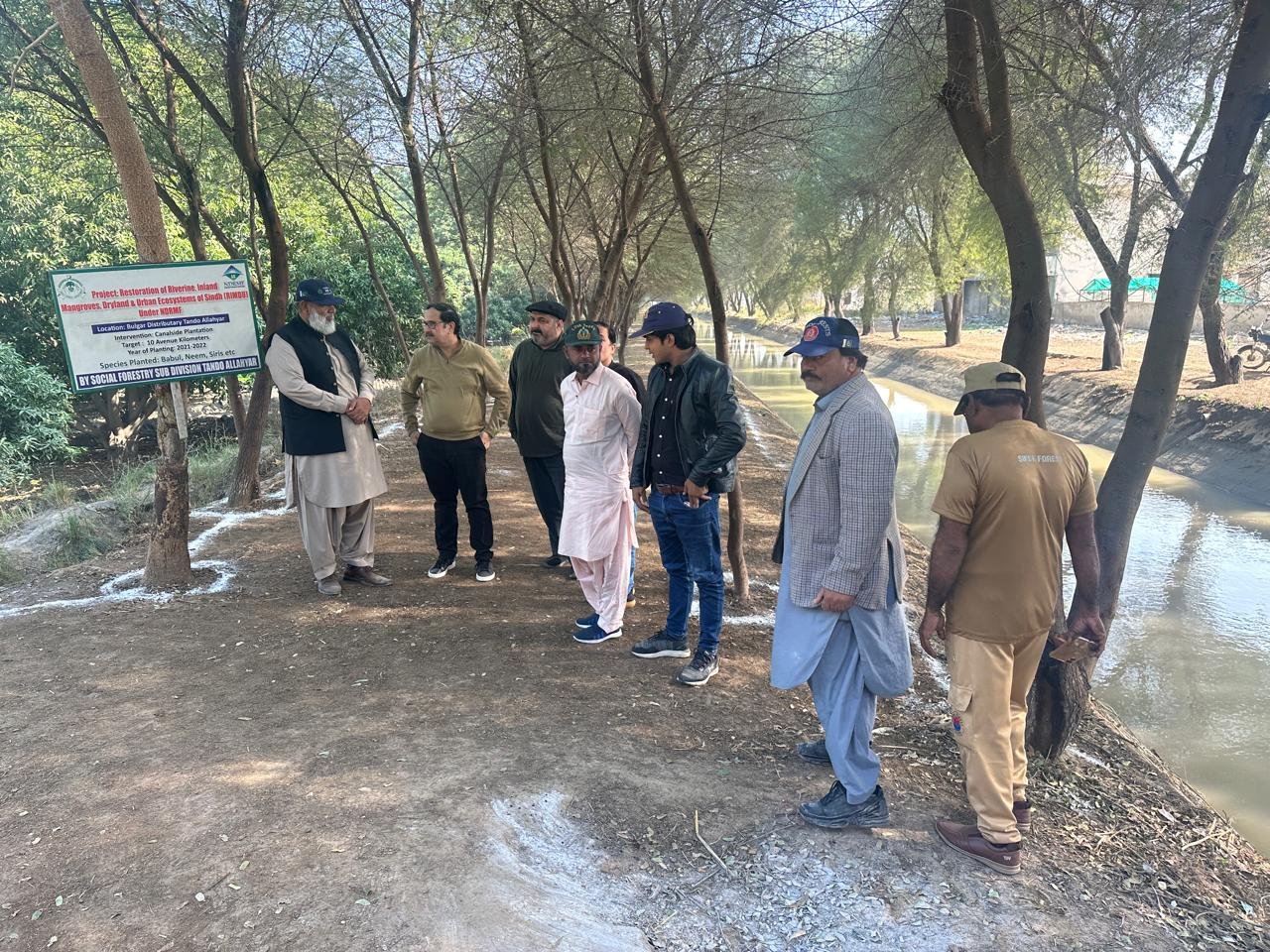 A site party beside the signboard for the RIMDU canalside plantation on the Bulgar Distributary at Tando Allahyar, Sindh